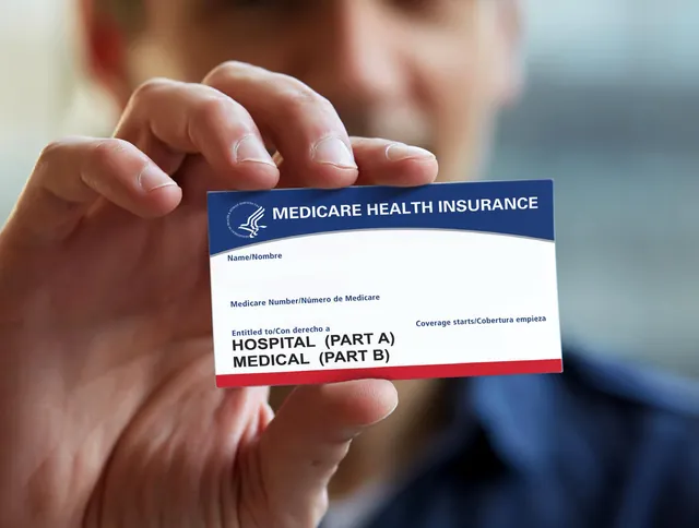 Hand holding a blank red, white and blue Medicare card