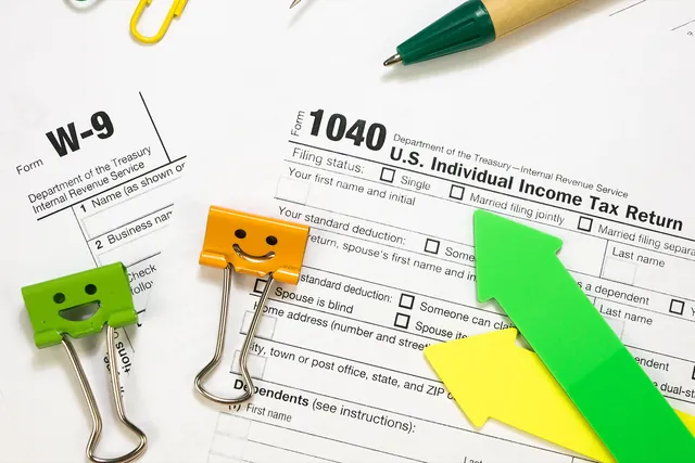 Form 1040 and W-9 tax forms with binder clips
